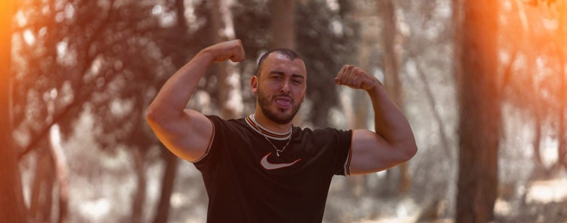 a man flexing his muscles in the woods