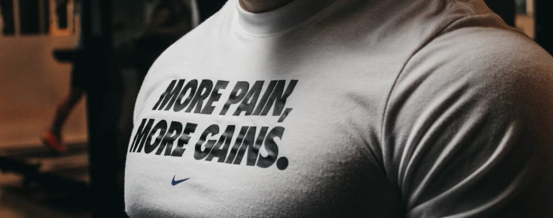 Close-up of a muscular man in the gym wearing a t-shirt with an inspiring fitness message.